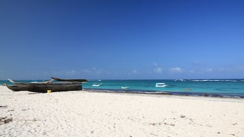 Na praia, areia branca, espreguiçadeiras, guarda-sóis