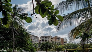 A hotel with multiple floors, surrounded by lush greenery and palm trees. - Diani Beachfront Paradise (Diani Beach)