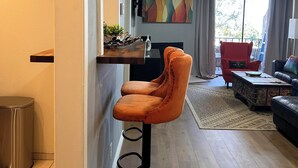 Una sala de estar moderna con suelo de madera, un sillón rojo, un sofá negro y una mesa de centro.