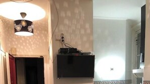 Une cuisine avec un plan de travail noir, une chaise noire, un petit meuble noir et un luminaire.
