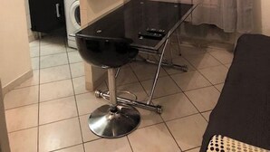 Une cuisine compacte équipée d’un évier, d’un lave-linge et d’un coin repas avec une table et des chaises.