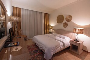 Une chambre d’hôtel équipée d’un lit, de lampes de chevet, d’une télévision, d’une chaise et d’un bureau avec une télécommande.