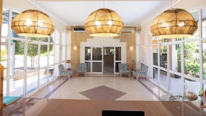 A spacious lobby with large windows, three hanging lamps, and several chairs. - Paradise Kitesurfing Hotel (Ras Sudr)