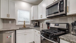 A modern kitchen with white cabinets, stainless steel appliances, and granite countertops. - Charming 6-bedroom house with AC in Houston (Houston)