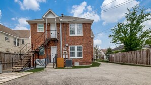A two-story brick house with a front porch, a staircase, and a fenced yard. - Charming 6-bedroom house with AC in Houston (Houston)