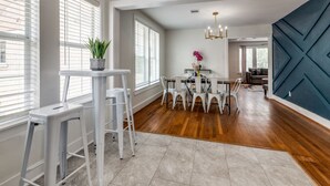 A modern kitchen with a dining area, featuring a central island, white chairs, and a chandelier. - Charming 6-bedroom house with AC in Houston (Houston)
