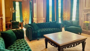 A room with a green upholstered sofa, a wooden coffee table, and a fireplace.