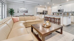 Una cocina moderna con gabinetes blancos, electrodomésticos de acero inoxidable y una isla central con taburetes.
