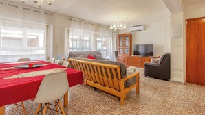 Ein Wohnzimmer mit Essbereich, einer Couch, einem Fernseher und einem Schrank.