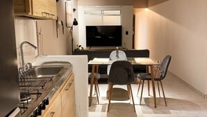 A compact kitchen with a dining area, wooden cabinets, a built-in stove, and a ceiling fan. - Spacious 3-bedroom apartment with AC, Laureles-Estadio, Terrace (Medellín)
