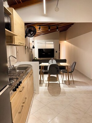 Eine kompakte Küche mit Essbereich, Holzschränken, Einbauherd und Deckenventilator.