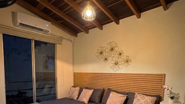 A bedroom with a large bed, a ceiling fan, and a view through a sliding door. - Spacious 3-bedroom apartment with AC, Laureles-Estadio, Terrace (Medellín)