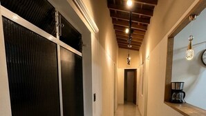 A hallway with a tiled floor, a window with blinds, a coffee machine on a shelf, and a ceiling with exposed beams. - Spacious 3-bedroom apartment with AC, Laureles-Estadio, Terrace (Medellín)