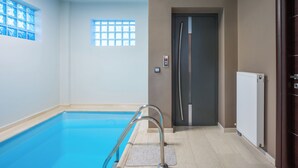 Une piscine avec une paroi en verre, une porte dotée d’une poignée et un radiateur fixé au mur.