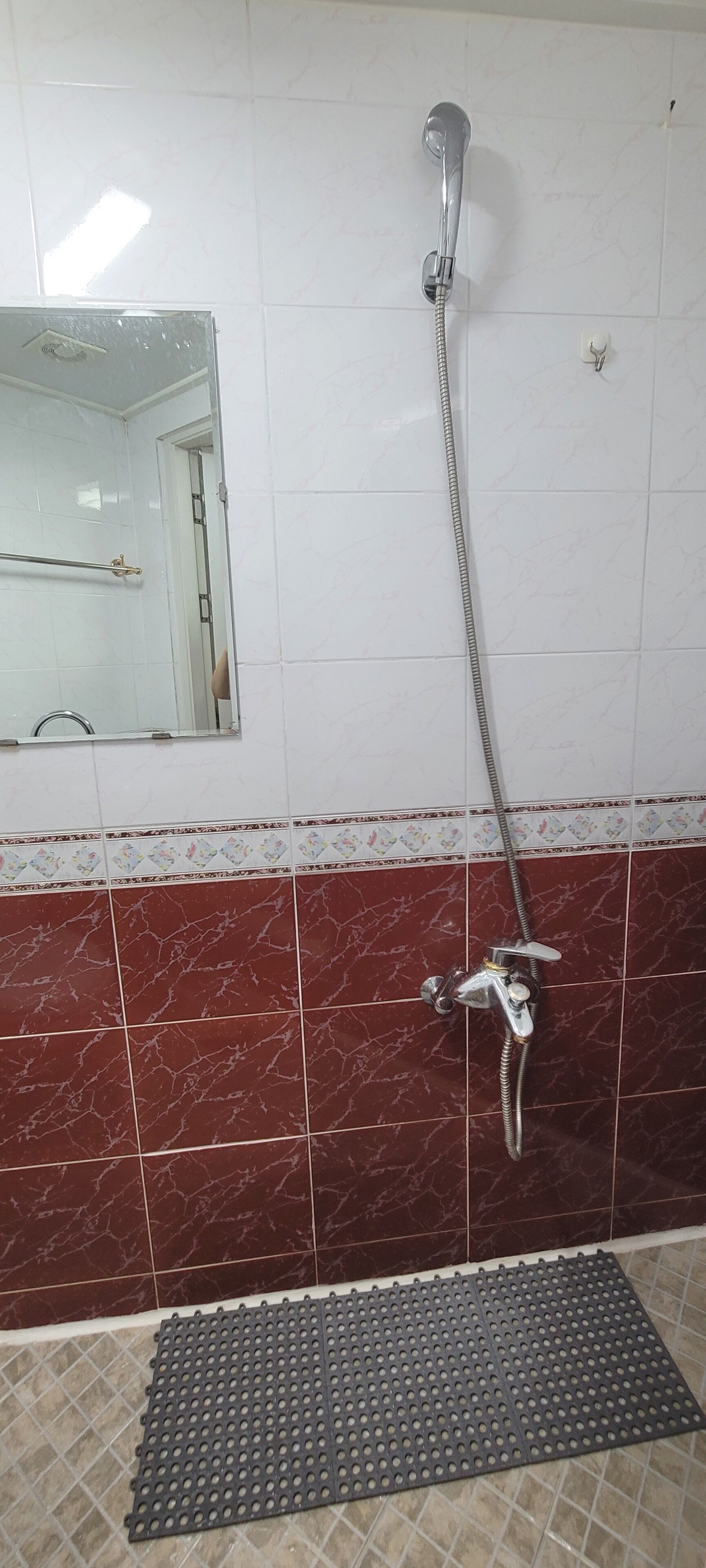 A bathroom with a shower, a mirror, and a tiled floor.