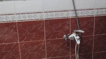 A bathroom with a shower, a mirror, and a tiled floor.