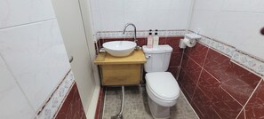 Une petite salle de bain avec un lavabo blanc, des toilettes et un meuble-lavabo en bois.