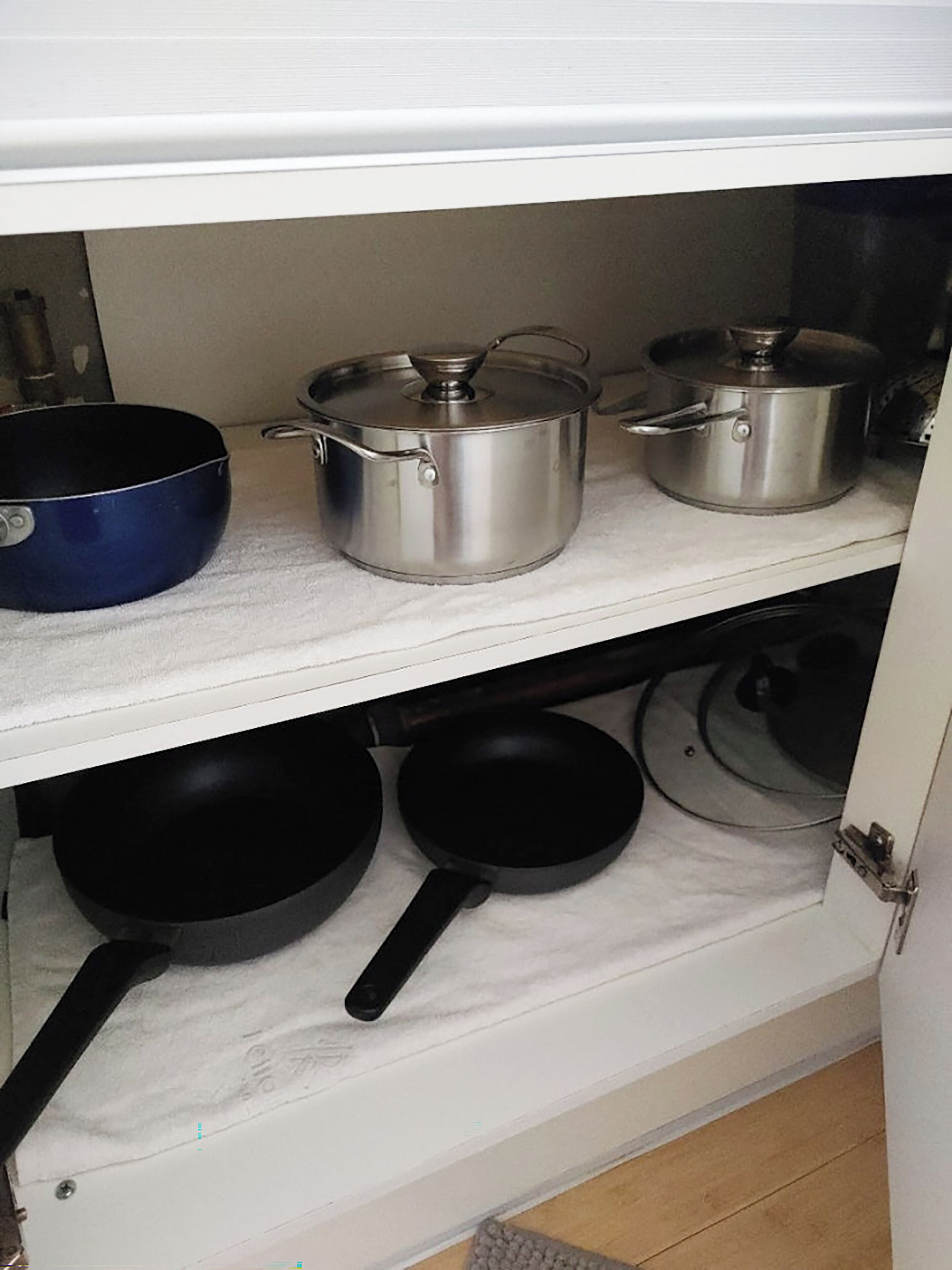 A kitchen with stainless steel cookware on shelves, including pots and pans.