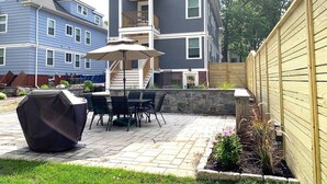 Un patio con una parrilla, una mesa y sillas al aire libre.
