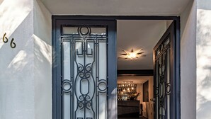 A modern entrance with a decorative metal gate, a stone pathway, and a well-lit interior visible through the doorway. - CASA NOU (Mexico City)
