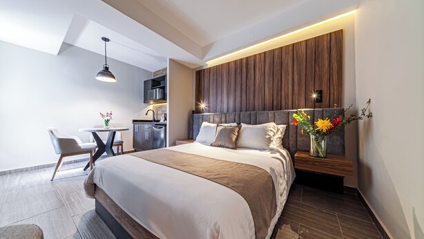 A modern hotel room with a large bed, a desk, and a kitchenette. - CASA NOU (Mexico City)