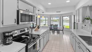 Una cocina moderna con electrodomésticos de acero inoxidable, un comedor con vista a un lago y una planta colgante.
