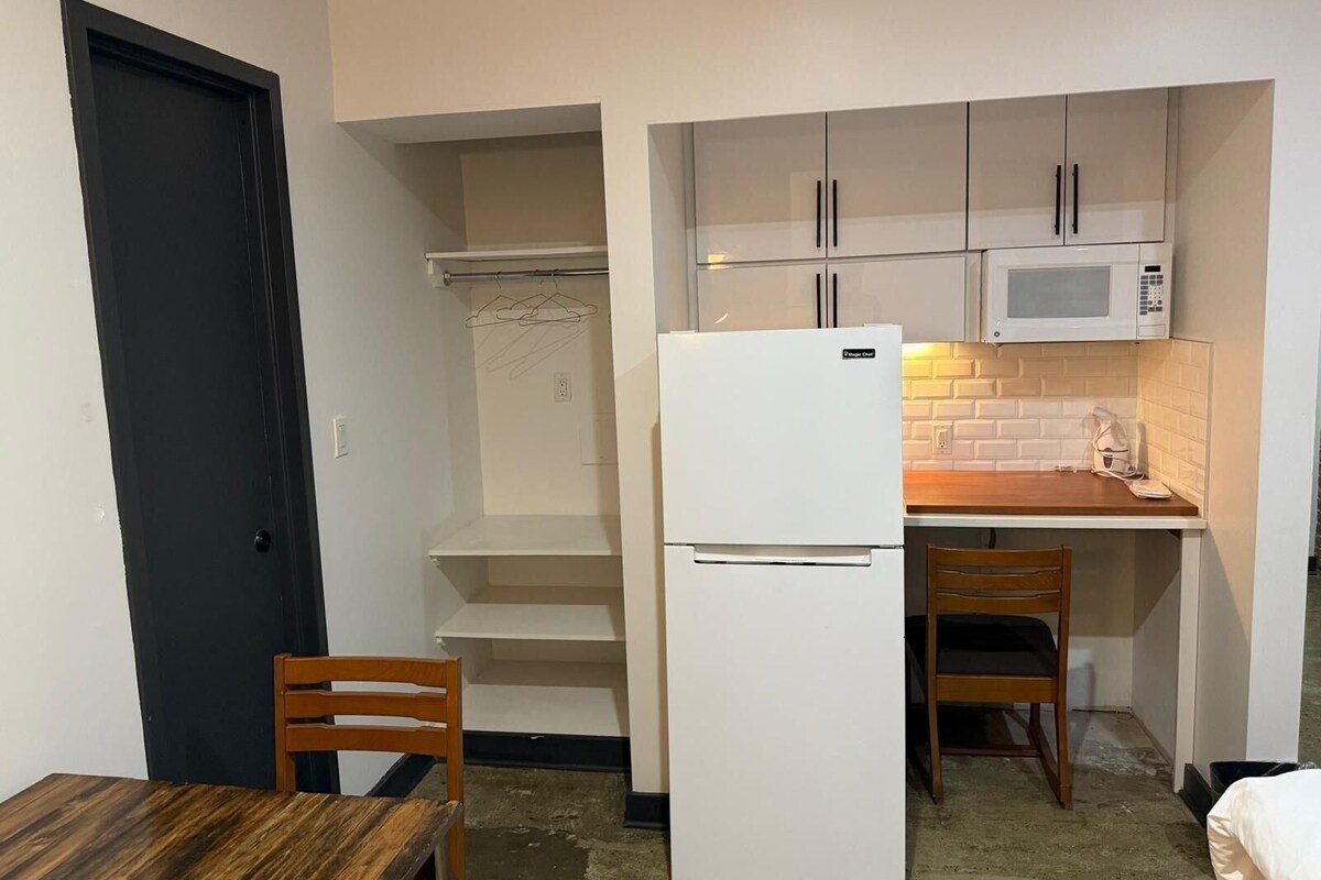 A compact kitchen with a refrigerator, microwave, and wooden dining table.