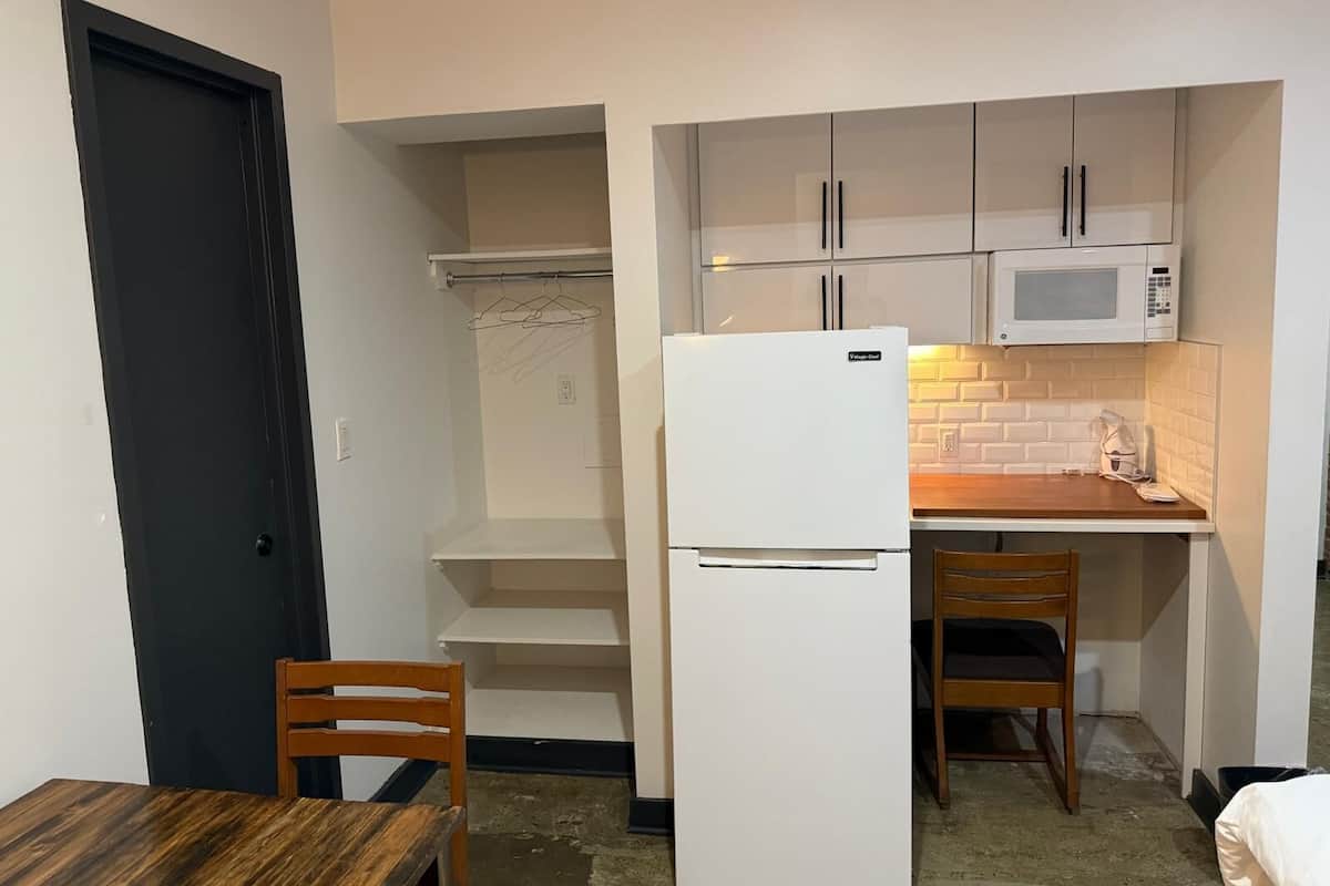A compact kitchen with a refrigerator, microwave, and wooden table.