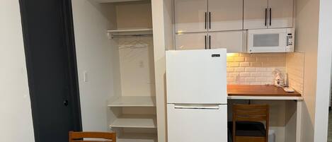 A compact kitchen with a refrigerator, microwave, and wooden table.
