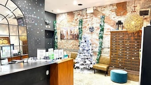 A reception area with a modern desk, a Christmas tree, and a brick wall.