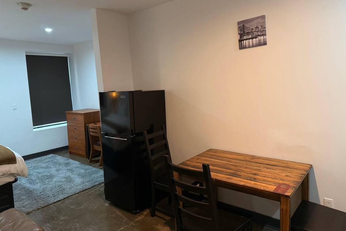 A compact kitchen with a black refrigerator, wooden dining table, and chairs.