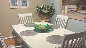 A dining area with a white table and chairs, a decorative bowl, and a potted plant.