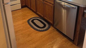 A kitchen with wooden cabinets, a stainless steel dishwasher, a microwave, a stove, and a sink.