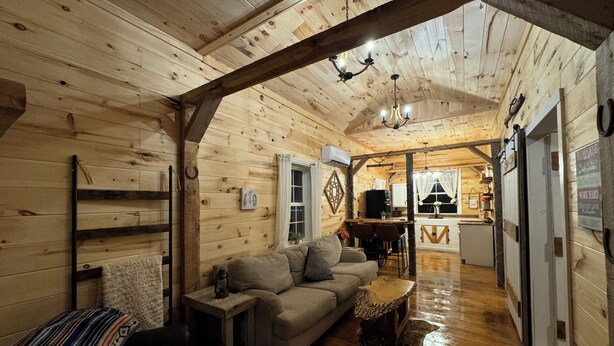 L’intérieur d’un chalet confortable en bois, avec un salon, un coin repas et une cuisine.