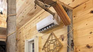 Un intérieur rustique en bois, avec une table et des chaises, un élément décoratif mural et un appareil de climatisation.
