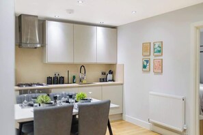 A modern kitchen with a dining area, stainless steel appliances, and a white radiator. - City flat near Brick Lane w/ kitchen & dining (Greater London)