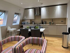 A modern kitchen with stainless steel cabinets, a dining area with striped chairs, and a small white chair. - City flat near Brick Lane w/ kitchen & dining (Greater London)