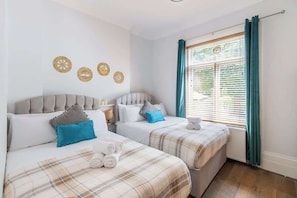 A hotel room with two beds, a window with curtains, and wall decorations.