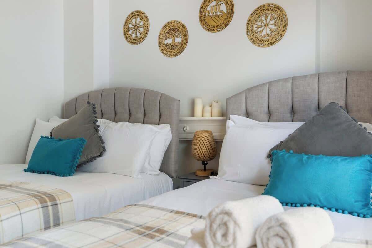 Une chambre d’hôtel avec deux lits, une table de chevet avec une lampe et des œuvres d’art décoratives au mur.
