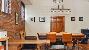 A dining area with a wooden table and chairs, a brick wall, and a wooden door.