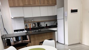 Een moderne keuken met witte kastjes, een zwart aanrecht en een witte eettafel met vier stoelen.