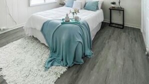 A bedroom with a bed, a nightstand, a lamp, and a painting on the wall.