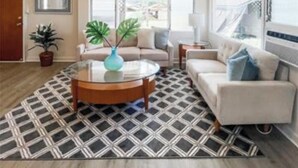 A modern living room with a round coffee table, a sofa, and a patterned rug.