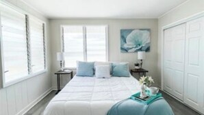 A bedroom with a bed, a nightstand, a lamp, and a window.