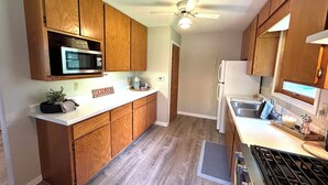 A kitchen with wooden cabinets, a microwave, a coffee maker, and a stove.