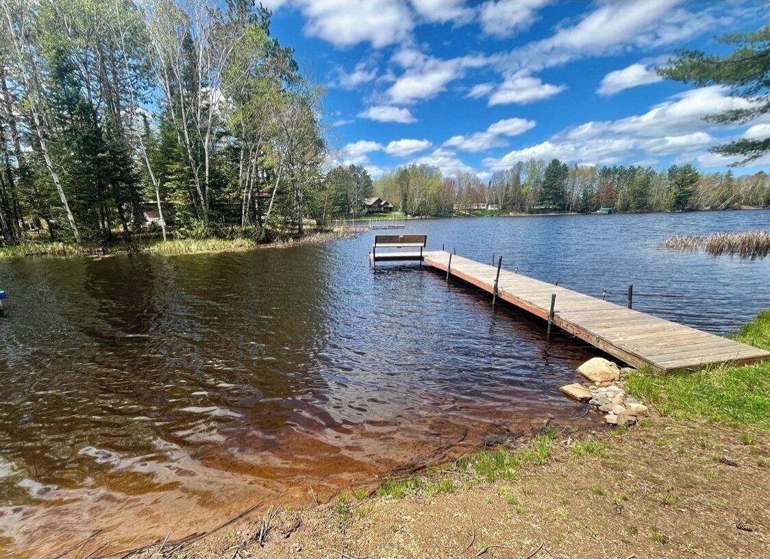 Un molo di legno che si protende su un lago circondato da alberi.