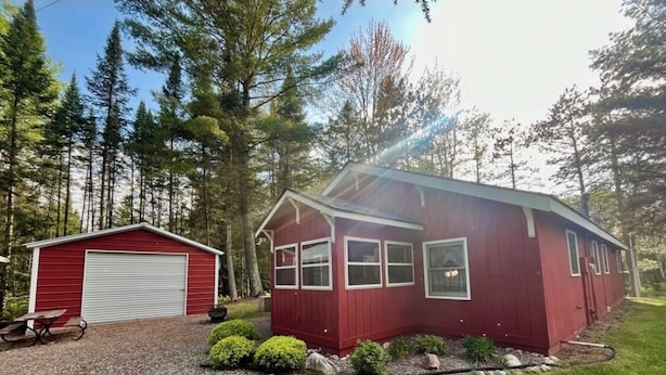 A red building with a garage, surrounded by a well-maintained lawn and trees.