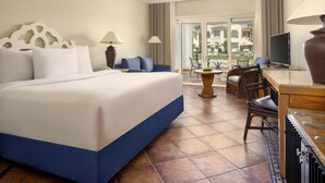 Een hotelkamer met een groot bed, een bureau met een televisie en uitzicht op de omgeving door een glazen deur.