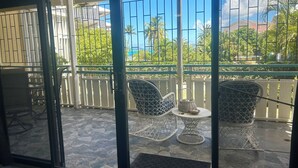 Un balcon avec deux fauteuils en osier, une petite table ronde et une grille en métal.