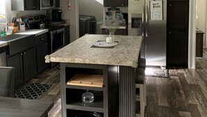 Una cocina moderna con armarios oscuros, una isla central y un refrigerador de acero inoxidable.